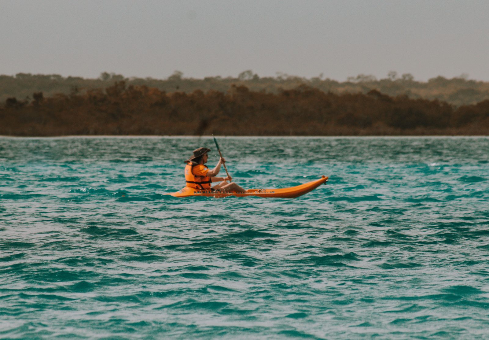 Una persona en kayak sobre aguas turquesa tranquilas en la Laguna de Bacalar