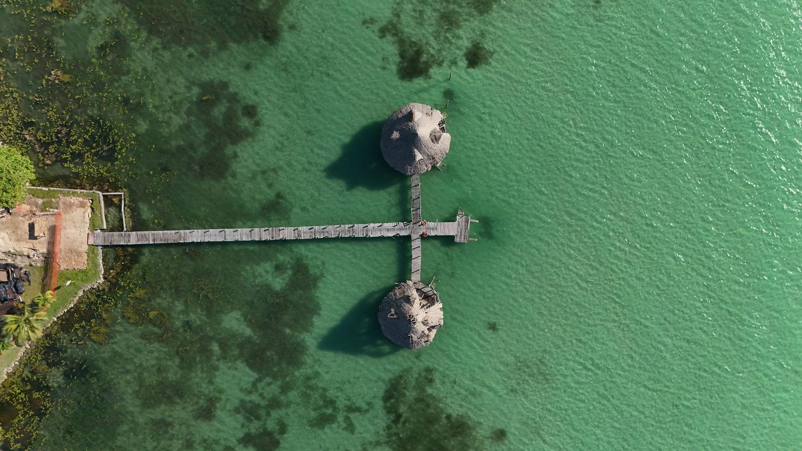 Vista aérea de la Laguna de Bacalar con franjas de agua turquesa y azul profundo junto a la selva verde