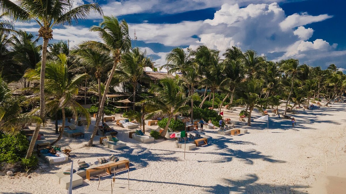 Ziggy Beach club in Tulum with bohemian loungers and daybeds under palm trees on white sand