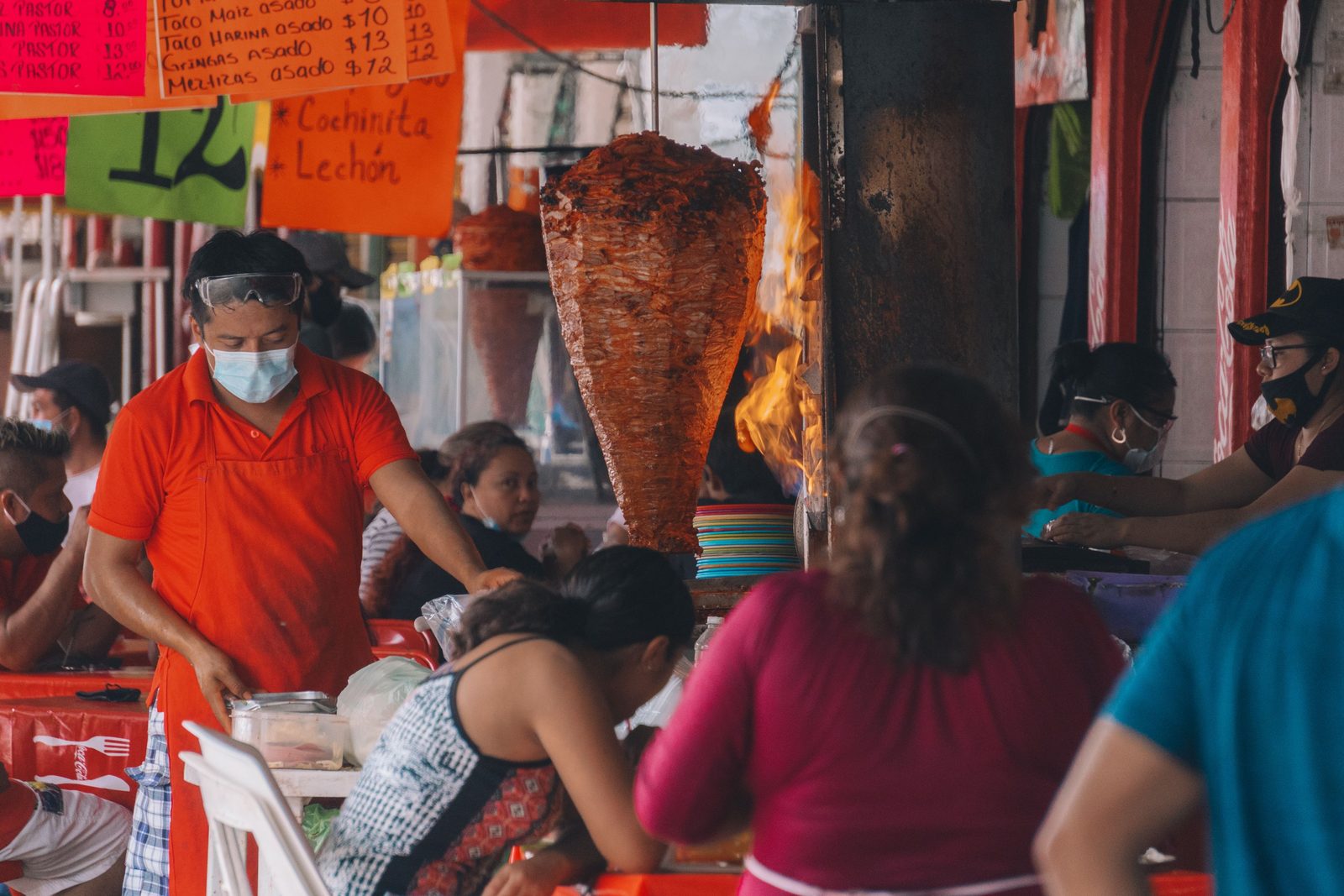 Taco stall inside a busy M&eacute;rida market with a spit of pork