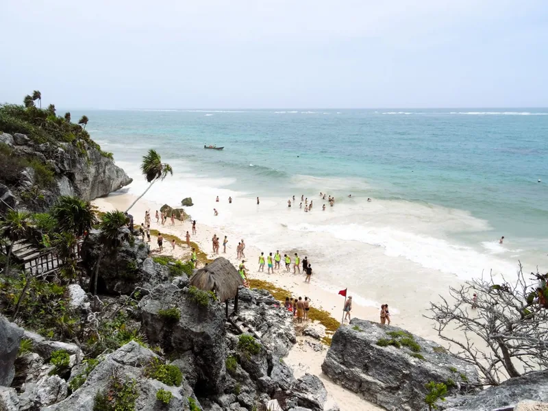 Tulum ruins beach seen from the cliff, swimmers in turquoise water