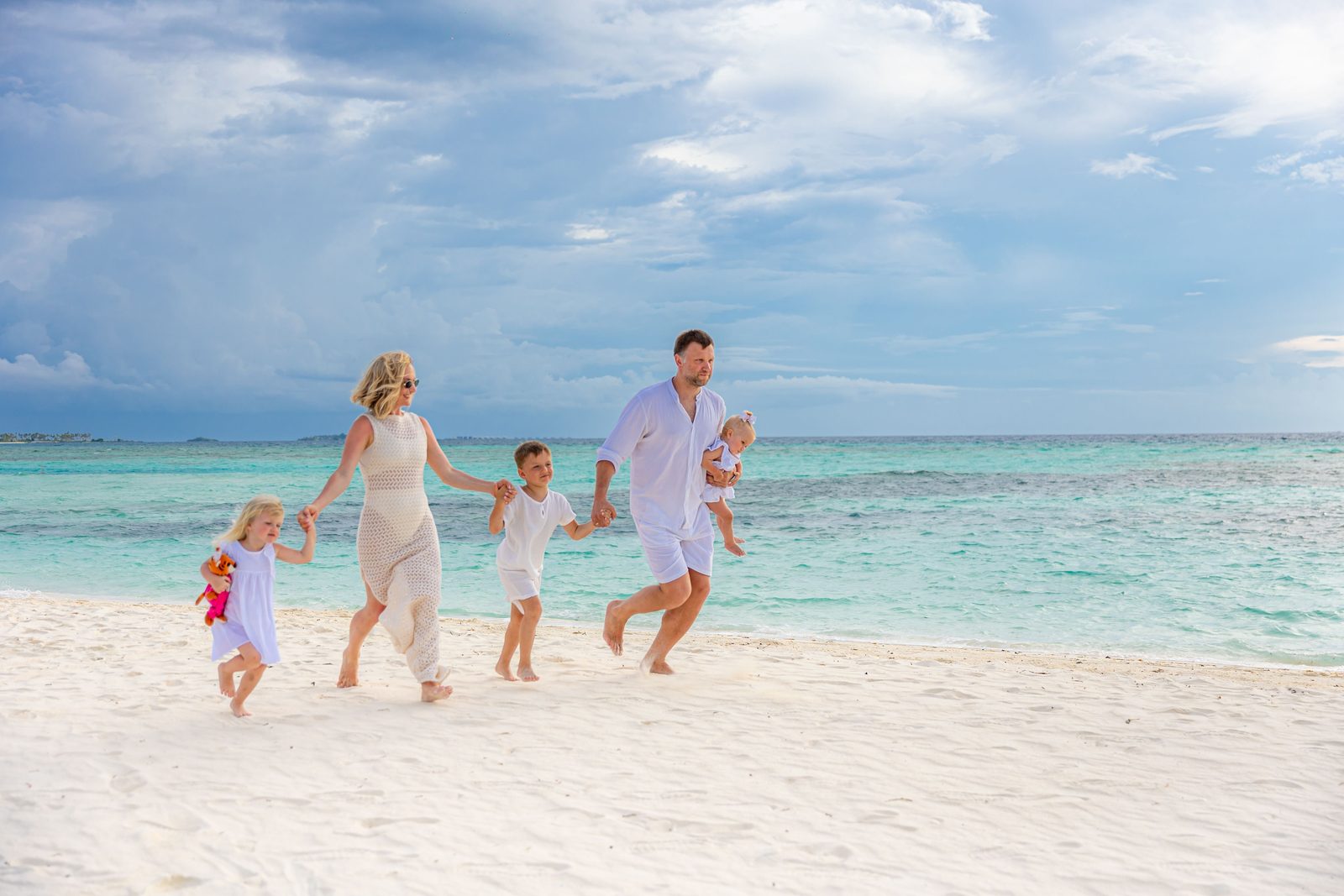 Famille avec de jeunes enfants marchant sur une plage de sable blanc à Tulum